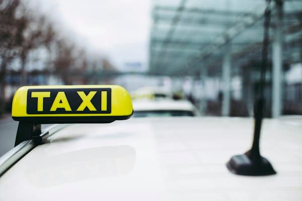 A taxi sign on the roof of a cab at the airport