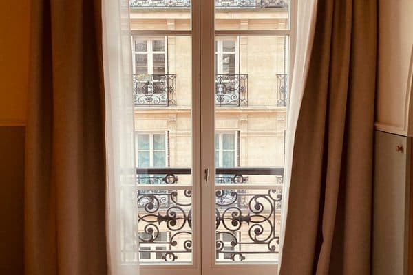 A Paris hotel room with a bed beside a tall window