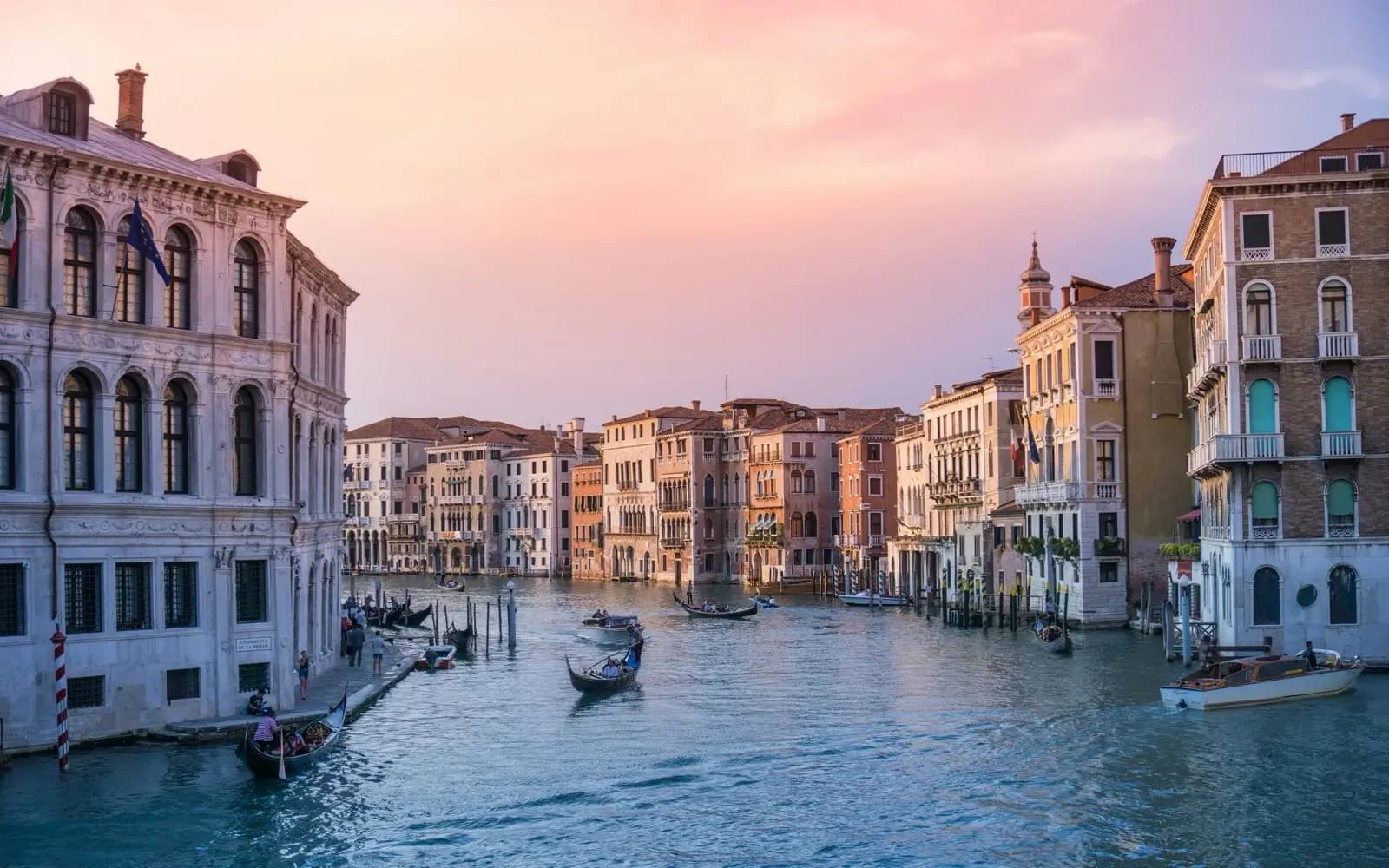 Gondolas and water taxis on Venice's Grand Canal at sunset, lined with palazzo facades