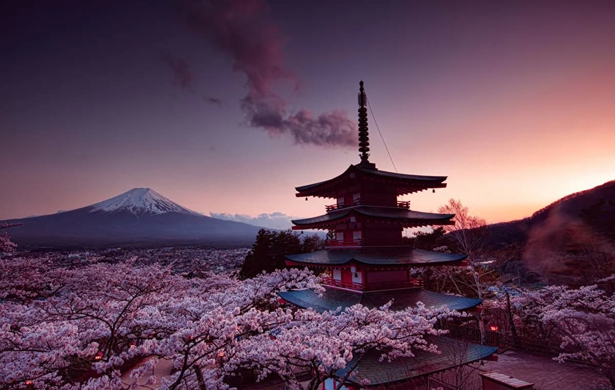 The Chureito Pagoda framed by cherry blossom at sunset, with Mount Fuji beyond