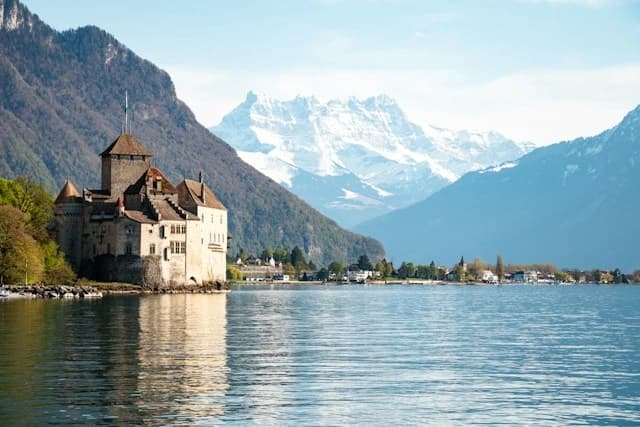 Chillon Castle standing in the water with the Alps behind it