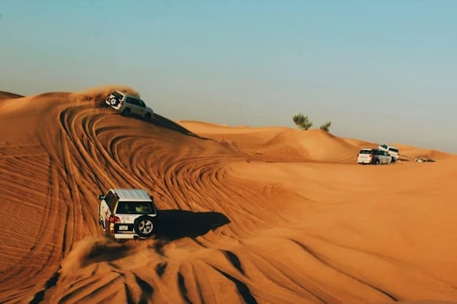 A 4x4 on a red dune in the morning