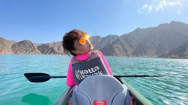 A kayak on the turquoise Hatta Dam water with the mountains behind