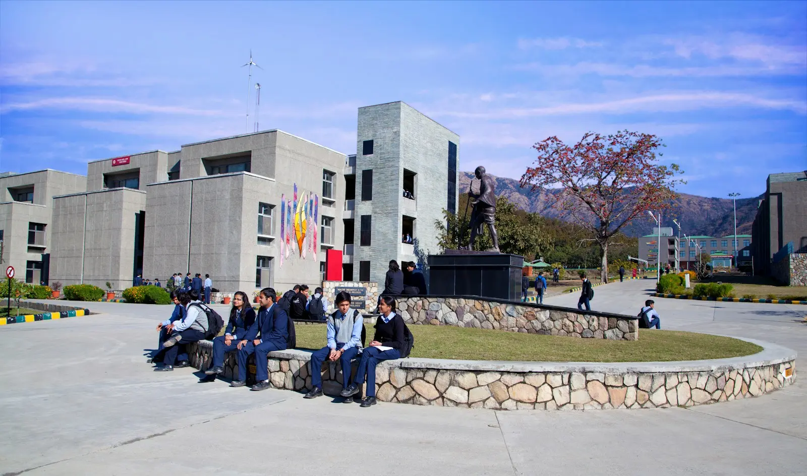 Students on the lawn of an Indian university campus, hills behind