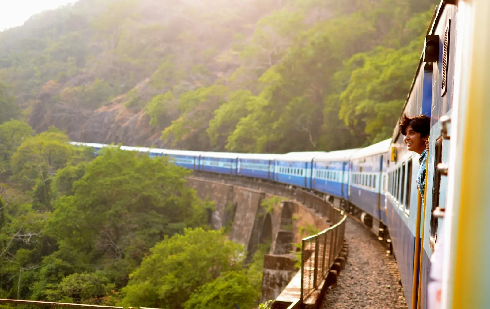 A passenger train crossing green hills in India